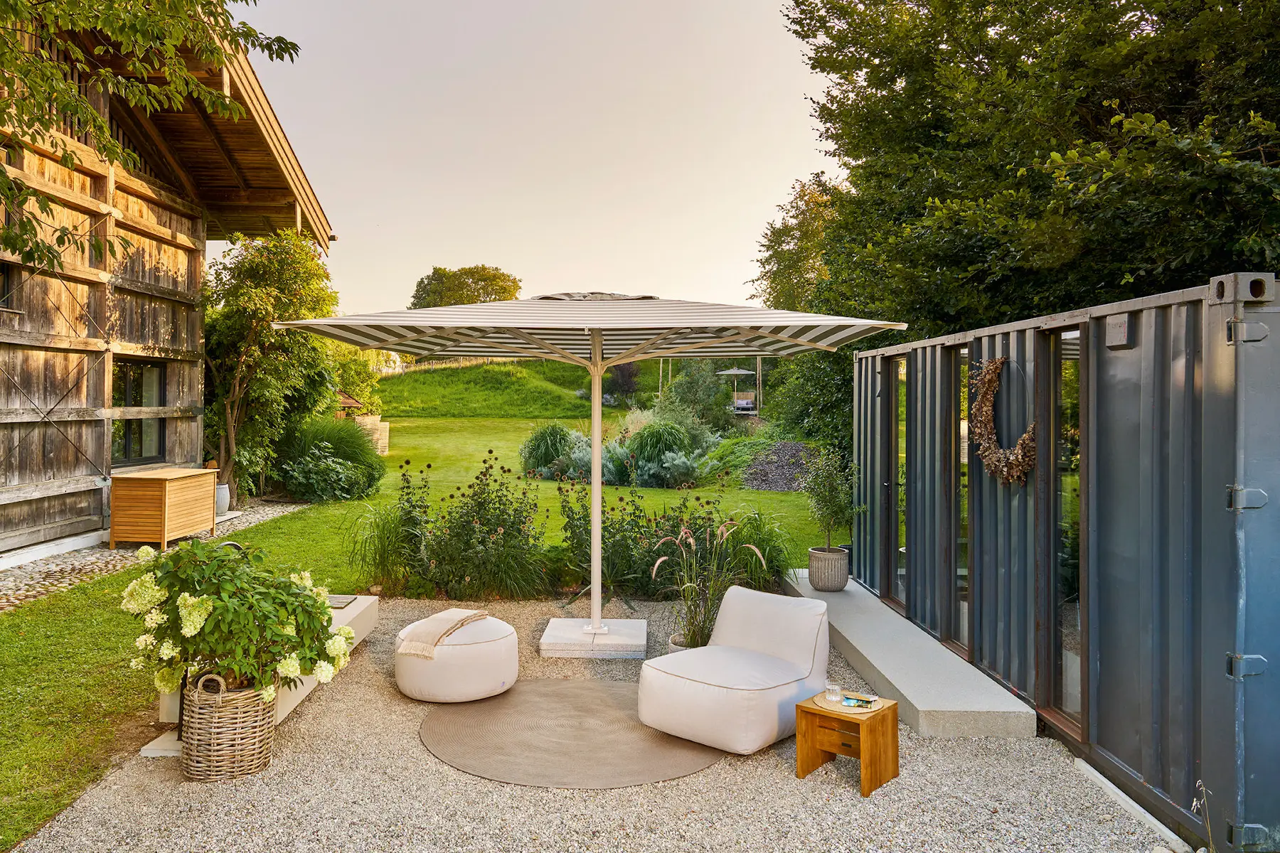 Weishäupl Teleskopschirm 400 x 400 cm mit grau-weiß gestreiftem Schirmdach in moderner Gartenlounge mit Loungemöbeln