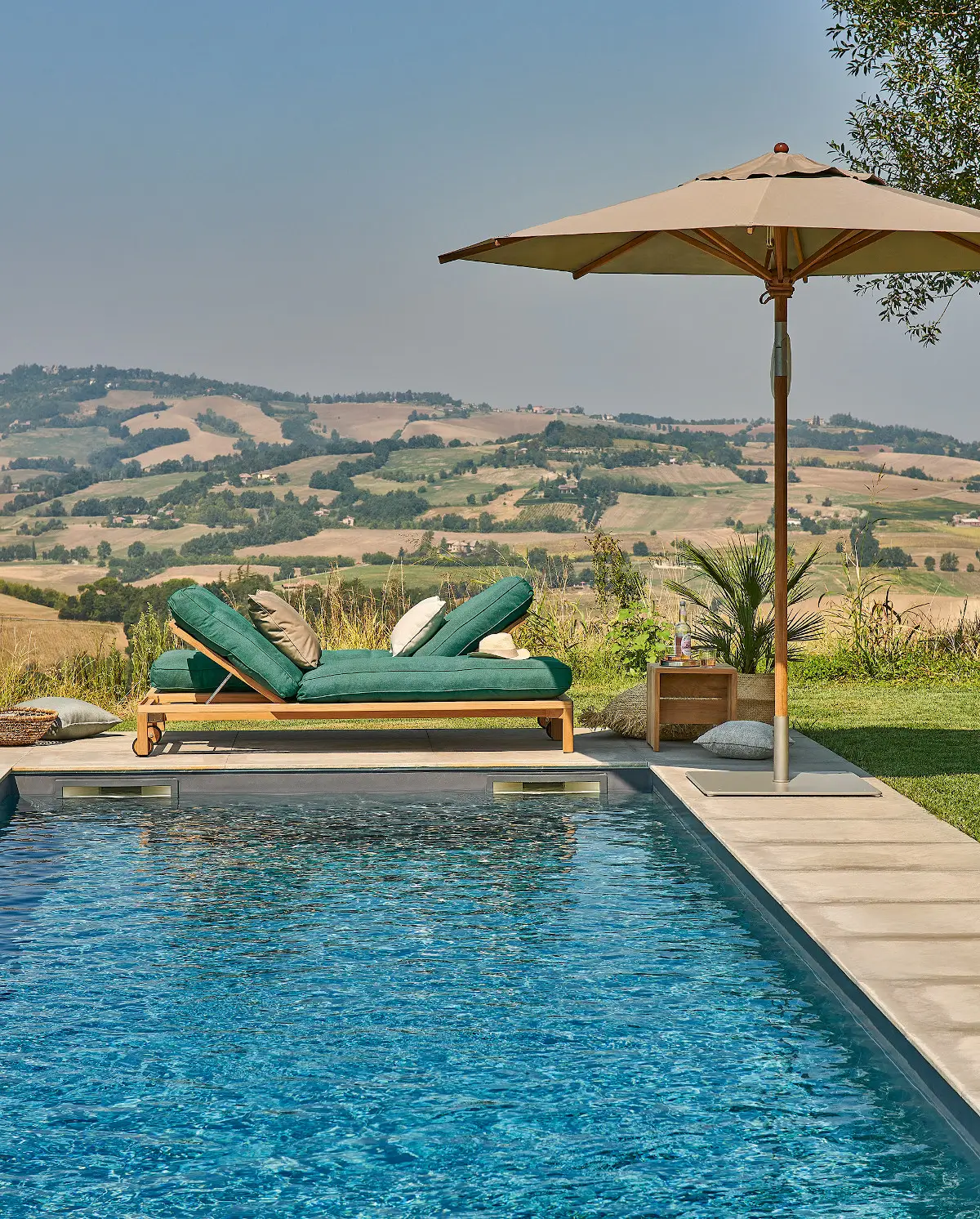 Weishäupl Teakschirm Ø 250 cm in Taupe neben einer Sonnenliege an einem Pool mit Panoramablick