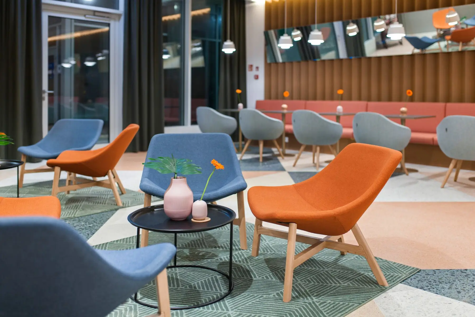 Noti Mishell Sessel mit Holzbeinen in Orange und Blau in einem modernen Hotel-Loungebereich