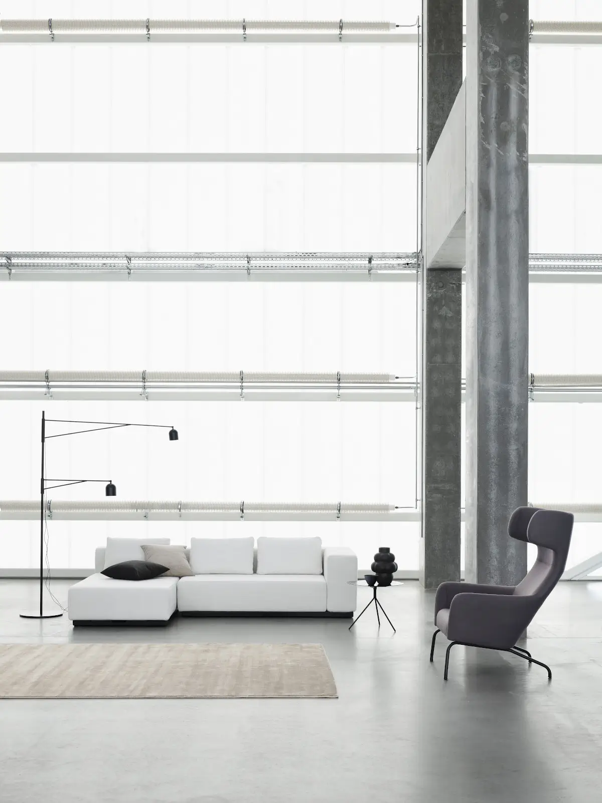 Softline Nevada Sofa 2-Sitzer in Hellgrau mit Chaiselongue, Kissen und schwarzem Sockel in einem großzügigen modernen Wohnambiente.