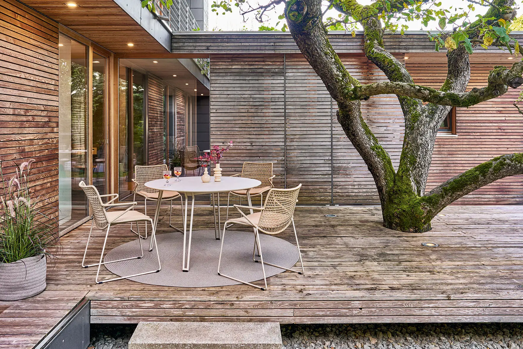 Weishäupl Slope Sessel in Perlbeige mit rundem Gartentisch – elegante Outdoor-Sitzgruppe für Terrasse und Garten.