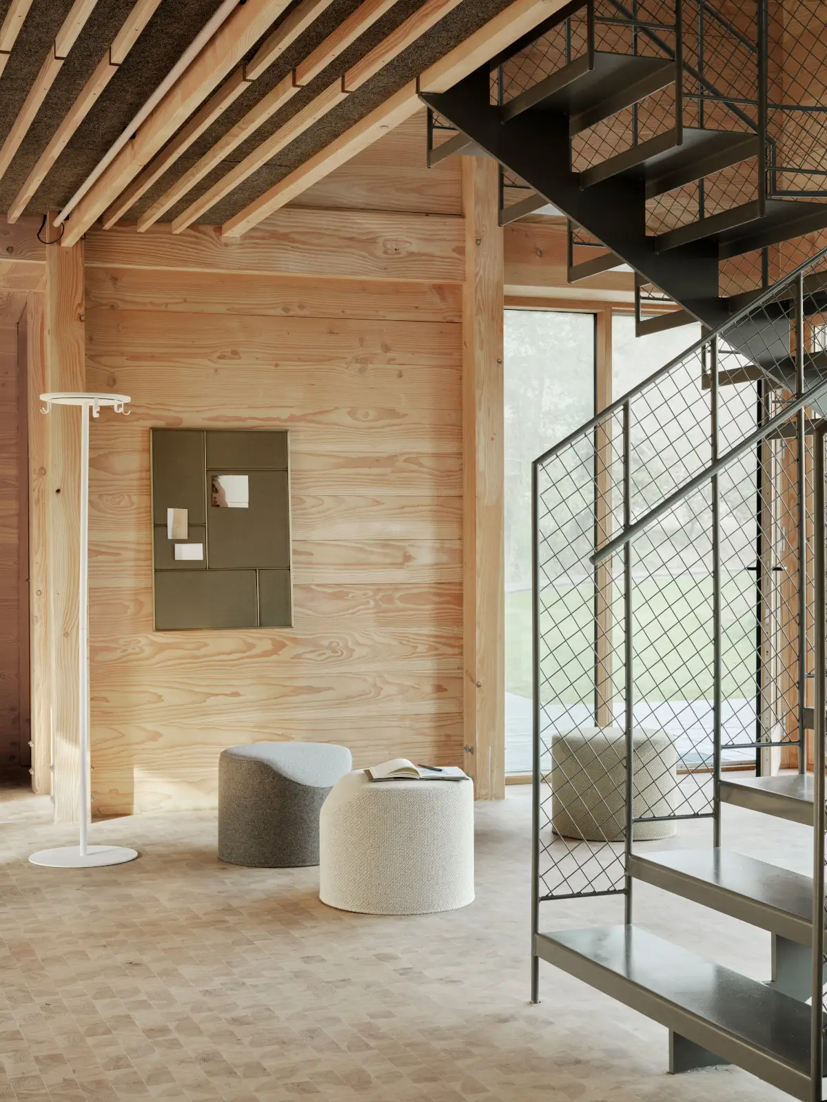 Softline Coral Hocker in Beige als Detailansicht mit strukturierter Polsterung und weich gerundeter Sitzfläche vor einer Holzwand.
