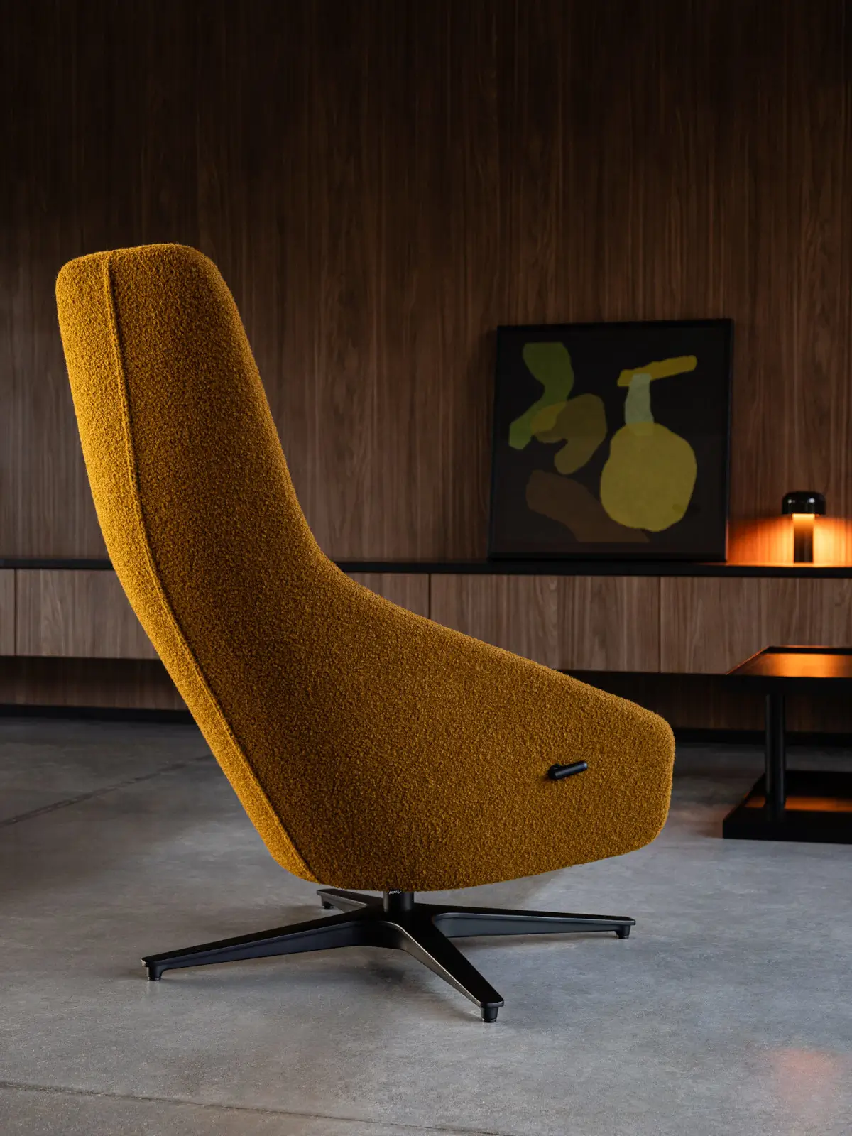 Noti Palo Sessel in Ocker mit schwarzem Kreuzgestell in einer modernen Lounge mit dunkler Holzwand