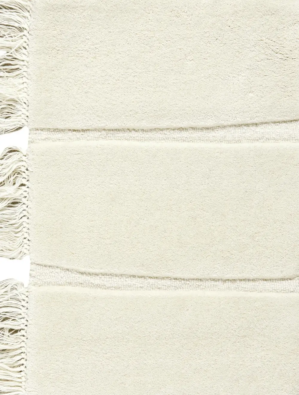 Massimo Copenhagen Atoll Teppich in Cream aus der Nähe mit weicher, heller Oberfläche, schmalen Strukturstreifen und Fransen am Teppichrand.