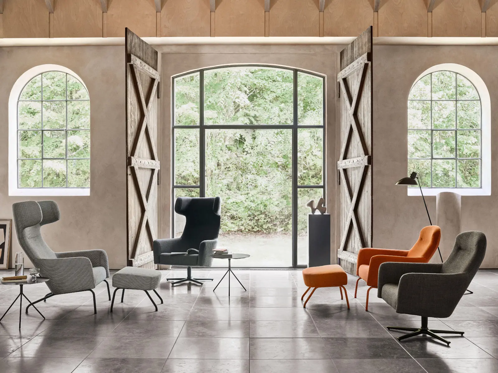 Mehrere Softline Havana Drehsessel in Grau, Dunkelgrau und Orange mit unterschiedlichen Gestellen und passenden Hockern in einem großzügigen Wohnambiente.