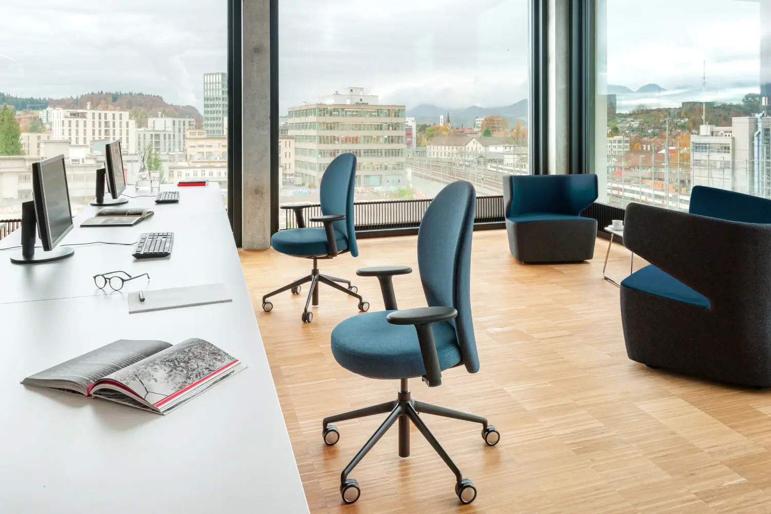 Girsberger Pablo Sessel als komfortable Sitzgelegenheit neben einem großzügigen Arbeitsplatz.