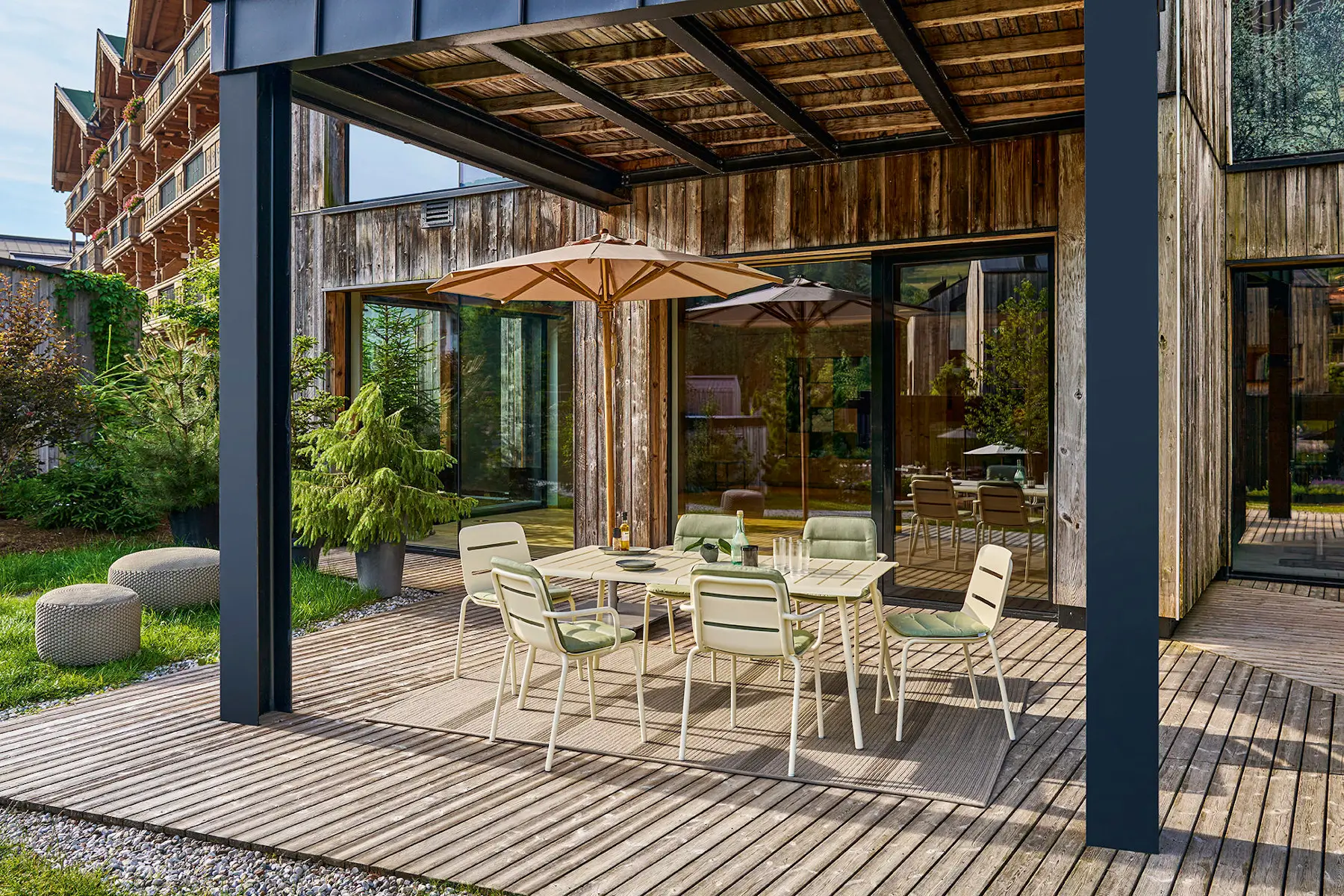 Weishäupl Teakschirm Ø 300 cm als Sonnenschutz über einem Esstisch auf einer modernen Holzterrasse