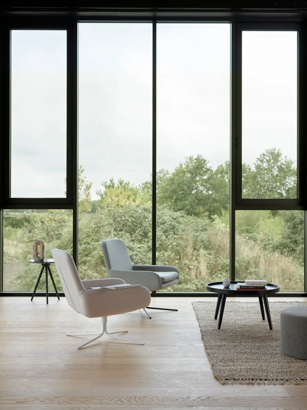Zwei Softline Coco Drehstühle in hellen Farbtönen in einem modernen Wohnzimmer mit großer Fensterfront, Holzboden, Teppich und Couchtisch.